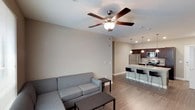 This single-floor residence offers a well-designed layout with modern finishes throughout. The open-concept living and kitchen area serves as the heart of the unit, where wood-look flooring, neutral warm-toned walls, and recessed lighting create a cohesive, contemporary atmosphere. A ceiling fan with a light fixture anchors the living space, which flows naturally toward large windows that allow ample natural light to fill the room.

The kitchen is a standout feature, centered around a large granite-topped island with bar seating for multiple guests. Dark espresso cabinetry reaches toward the ceiling, providing generous storage, while a full suite of stainless steel appliances — including a refrigerator, range, and microwave — adds a polished, functional quality. Pendant lights hang above the island, complementing the recessed ceiling fixtures.

Both bedrooms are carpeted or finished with wood-look flooring and include ceiling fans, closet space, and windows with blinds for natural light and privacy. Each bedroom is served by its own bathroom, both of which feature dark wood vanities, white countertops, tub-shower combinations, and wood-look flooring, maintaining a consistent design language throughout the unit.