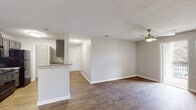 Located at 317 Lynn Rd in Raleigh, NC, this single-floor unit offers a well-organized layout designed for comfortable everyday living. The open-concept living and dining area is finished with rich hardwood-style flooring and neutral gray walls, creating a clean, versatile backdrop. A ceiling fan adds both function and character overhead, while a sliding door provides direct access to a private outdoor deck, bringing in natural light and a seamless indoor-outdoor connection.

The galley kitchen runs alongside the living area and features dark gray cabinetry, black appliances including a refrigerator, range, and dishwasher, and a granite-style countertop with a double sink. A peninsula counter opens toward the main living space, making the kitchen feel connected rather than enclosed.

The bedrooms are carpeted for warmth and comfort, each equipped with a ceiling fan and generous closet space. One bedroom benefits from a pair of windows that invite natural light and offer views of the surrounding greenery.

Two full bathrooms serve the unit, each featuring wood-style tile flooring, a tub-shower combination with white tile surround, a granite-topped vanity with gray cabinetry, and a framed mirror. The textured ceilings throughout lend a consistent finish across the space, tying the interior together with a cohesive, functional aesthetic.