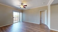 Located at 3131 SW 89th St in Oklahoma City, Oklahoma, this single-story home offers a thoughtfully designed layout with a blend of comfort and modern finishes throughout. The spacious living area features warm hardwood-style flooring, crown molding, and a ceiling fan with light fixture, creating an inviting atmosphere. Sliding glass doors open directly onto a private balcony, allowing natural light to fill the room and offering pleasant outdoor views. The kitchen is equipped with gray cabinetry, stone-look countertops with a breakfast bar, stainless steel refrigerator, and a built-in microwave, all complemented by light hardwood-style flooring. An adjacent dining or flex space features a distinctive tray ceiling with crown molding detail, adding architectural character. The bedrooms are carpeted for comfort, with ceiling fans providing additional airflow, and windows dressed with blinds for privacy. One bedroom benefits from direct access to a well-appointed bathroom featuring a stone-topped vanity with gray cabinetry, a walk-in closet with built-in shelving, and tiled shower walls. Additional carpeted rooms provide flexible use as bedrooms or office spaces. The home presents a clean, neutral palette throughout, making it move-in ready.