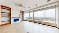 Located at 1324 Elm St in downtown Dallas, this thoughtfully designed 2-bedroom, 5-bathroom residence offers generous living space across a single level. Light-toned hardwood flooring flows throughout the main living areas, complementing the clean, modern aesthetic found in every room.

The open living room is a standout, featuring floor-to-ceiling windows that frame sweeping views of the Dallas skyline, a central fireplace flanked by warm wood built-in shelving, and a ceiling fan overhead. The space is bathed in natural light, creating a bright and airy atmosphere.

The chef's kitchen is outfitted with sleek slate-blue cabinetry, quartz countertops, a marble-inspired backsplash, stainless steel double wall ovens, a gas cooktop, and a large center island — ideal for both cooking and entertaining.

The spacious primary bedroom features elevated ceilings, recessed lighting, and a ceiling fan, while the second bedroom also enjoys direct access to panoramic city views. Both bedrooms are supported by well-appointed bathrooms, including a luxurious primary bath with a freestanding soaking tub, a glass-enclosed shower clad in dark stone tile, and a wood-framed vanity with marble countertops.

Two walk-in closets provide ample storage, and a dedicated laundry room adds everyday convenience to this refined urban residence.