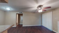 This single-story, 1-bedroom, 1-bathroom residence in Houston, TX offers a practical and comfortable layout designed for efficient living. The entryway opens into a bright living area finished with rich, dark hardwood-style flooring that extends throughout the main living spaces. A ceiling fan with a light kit provides both airflow and illumination, while vertical blinds on a large sliding door allow for adjustable natural light. A white brick fireplace serves as a charming focal point in the living room, adding character and warmth to the space.

The galley-style kitchen is thoughtfully organized, featuring white cabinetry, granite-look countertops, a double-basin stainless steel sink, and white appliances including a coil-top electric range and a full-size refrigerator. A pass-through window connects the kitchen to the entryway area, enhancing the open feel.

The bedroom is generously sized and finished with plush carpeting for added comfort. It receives natural light through a window and offers ample wall space for furnishings. The full bathroom includes a tub-shower combination with a clean white surround, a toilet, and a vanity with matching granite-look countertops. The textured ceiling detail is present throughout, contributing to the home's classic character.