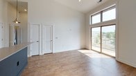 This well-appointed one-bedroom, one-bathroom residence in the Powderhorn neighborhood offers a thoughtfully designed layout across a single floor. Soaring ceilings throughout the unit create an impressive sense of openness and volume that extends well beyond the modest footprint.

The open-concept living and kitchen area serves as the heart of the home. The kitchen is outfitted with stainless steel appliances — including a French door refrigerator, electric range, and over-the-range microwave — complemented by white shaker cabinetry, a mosaic tile backsplash, and light quartz countertops. A peninsula with pendant lighting provides bar seating and separates the kitchen from the living area, which features warm hardwood-style flooring throughout.

The living area is bathed in natural light thanks to large sliding glass doors that open to a private balcony, offering views of the surrounding neighborhood. The soaring ceilings in this space further enhance the airy, loft-like ambiance.

The bathroom is finished with a dark espresso vanity, white countertop, a tiled tub-shower combination, and a large mirror. A stacked in-unit washer and dryer is conveniently located just off the bathroom, adding a practical touch to everyday living.