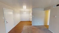 Located at 2825 W Walnut Hill Ln in Irving, TX, this single-floor unit offers a practical and well-organized layout designed for comfortable everyday living. The main living area features a combination of warm hardwood-style flooring and plush carpet, creating a welcoming atmosphere. A set of French doors at the far end of the living room fills the space with natural light and provides access to the outdoors. The open layout connects the living area to the dining space, which is accented by a pendant chandelier overhead. White cabinetry lines the adjacent kitchen, which is equipped with a coil-top electric range, a dishwasher, a refrigerator, granite-style countertops, and a single-basin sink — all finished in a clean, neutral palette. A hallway with wall sconce lighting leads to the bedroom, which is carpeted and features a ceiling fan with light fixture and a window overlooking the outdoors. The bathroom includes a large mirror, a speckled granite-style vanity countertop with white cabinetry below, and a full tub and shower combination with white tile surround. Textured ceilings are present throughout the unit, adding a classic touch to the overall design.