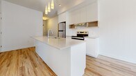 Located at 40 Kirkland Private in Ottawa, Ontario, this well-appointed one-bedroom, one-bathroom unit offers a thoughtfully designed single-floor layout. Light hardwood flooring flows throughout the main living areas, creating a warm and cohesive feel.

The kitchen is a standout feature, showcasing a sleek, modern design with a large central island topped with white quartz countertops and an undermount sink. Stainless steel appliances — including a refrigerator, electric range, and dishwasher — are complemented by white cabinetry, open wood shelving, subway tile backsplash, and a stylish pendant lighting cluster above the island. A range hood with under-cabinet lighting adds both function and style.

The bedroom is a comfortable, sun-filled retreat with a large window offering pleasant outdoor views and allowing generous natural light to pour in. Adjacent to the bedroom is a dedicated closet, providing practical storage. A hallway connects the rooms efficiently.

The bathroom is finished in neutral large-format tile flooring and tub surround, featuring a modern white vanity with a vessel sink and a full soaker tub, creating a clean and contemporary aesthetic.

Overall, the unit presents a bright, minimalist design with modern finishes throughout, making it a functional and attractive space in the Ottawa area.
