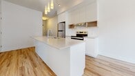 Located at 40 Kirkland Private in Ottawa, Ontario, this well-appointed one-bedroom, one-bathroom unit offers a thoughtfully designed single-floor layout. Light hardwood flooring flows throughout the main living areas, creating a warm and cohesive feel.

The kitchen is a standout feature, showcasing a sleek, modern design with a large central island topped with white quartz countertops and an undermount sink. Stainless steel appliances — including a refrigerator, electric range, and dishwasher — are complemented by white cabinetry, open wood shelving, subway tile backsplash, and a stylish pendant lighting cluster above the island. A range hood with under-cabinet lighting adds both function and style.

The bedroom is a comfortable, sun-filled retreat with a large window offering pleasant outdoor views and allowing generous natural light to pour in. Adjacent to the bedroom is a dedicated closet, providing practical storage. A hallway connects the rooms efficiently.

The bathroom is finished in neutral large-format tile flooring and tub surround, featuring a modern white vanity with a vessel sink and a full soaker tub, creating a clean and contemporary aesthetic.

Overall, the unit presents a bright, minimalist design with modern finishes throughout, making it a functional and attractive space in the Ottawa area.