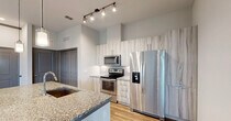 Located at 12501 Honore Ave in Sarasota, FL, this well-appointed two-bedroom, two-bathroom residence offers a thoughtfully designed single-level layout. The open-concept kitchen serves as the heart of the home, showcasing a large granite-topped island with a built-in sink, pendant lighting, stainless steel appliances including a French door refrigerator, electric range, and microwave, all complemented by light wood-toned cabinetry and a tile backsplash. Wood-look flooring flows through the main living areas, accented by crown molding and track lighting. The living area benefits from natural light and direct access to a private patio through a glass door, complete with a ceiling fan overhead. The primary bedroom features plush carpeting, tall ceilings, and dual windows that invite natural light and outdoor views. The second bedroom is similarly carpeted with a ceiling fan and ample closet space. Both bathrooms are finished with granite vanity countertops and wood-look flooring; one features a glass-enclosed walk-in shower, while the other offers a full tub-shower combo with subway tile surround. Additional highlights include a hallway, laundry area, dedicated utility space, and four closets for generous storage throughout.