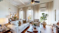 Located at 1450 Greene St in Augusta, Georgia, this single-floor loft-style unit showcases a compelling blend of industrial heritage and refined contemporary design. Rich hardwood floors run throughout, anchoring each space with warmth and continuity, while soaring ceilings with exposed ductwork and white-painted wood beam detailing reflect the building's historic character.

The open-concept living area is a standout, featuring a wall of tall windows dressed with sheer linen curtains that invite generous natural light and offer views of the surrounding neighborhood. A ceiling fan overhead and ample seating create a comfortable, airy atmosphere. The kitchen is well-appointed with stainless steel appliances, white cabinetry extending to the ceiling, a classic subway tile backsplash, and dark countertops. An integrated dishwasher and open shelving add both function and style.

The bedrooms are calm and well-proportioned, with high ceilings, closet storage, and original structural columns that serve as subtle nods to the building's past. The bathroom includes a tub and shower combination. A dedicated entry area transitions smoothly into the main living spaces, reinforcing the unit's thoughtful, flowing layout throughout.