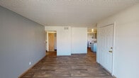 This single-floor unit offers a practical and well-organized layout designed for comfortable everyday living. The main living area features durable wood-look flooring and neutral-toned walls, creating a clean and versatile space. A textured ceiling runs throughout, adding a consistent design element across the unit.

The kitchen is efficiently arranged with ample grey cabinetry providing generous storage above and below the countertops. A double-basin sink, electric range with coil burners, a refrigerator, and a peninsula counter with a light blue base define the cooking and prep space. The peninsula offers additional workspace and a natural division between the kitchen and living area.

The bedrooms are carpeted for warmth and comfort, each featuring windows with vertical blinds that allow natural light to filter in. The rooms offer clean, neutral walls and textured ceilings, providing a blank canvas for personalization. At least one bedroom includes access to a closet.

Two full bathrooms serve the unit, each featuring wood-look flooring, a vanity with a speckled countertop, a toilet, and a tub-shower combination with white tile surround and a safety grab bar. The bathrooms are finished in a clean, functional style with consistent design details throughout.

Overall, the unit presents a straightforward, functional layout with cohesive finishes throughout.