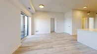 This well-appointed 2-bedroom, 2-bathroom unit offers a thoughtfully designed open-concept layout with a clean, contemporary aesthetic throughout. Light-toned hardwood flooring extends across the entire living space, complementing the bright white walls and creating a cohesive, airy feel.

The kitchen is a standout feature, equipped with stainless steel appliances including a refrigerator, electric range, and over-the-range microwave. Warm beige cabinetry provides ample storage, while a white quartz peninsula with pendant lighting above serves as both a functional workspace and a casual dining area. The kitchen flows seamlessly into the living room, which is bathed in natural light from large sliding glass doors that open to a private balcony offering open city views.

Both bedrooms are comfortably sized, featuring the same light hardwood flooring and large windows that bring in generous amounts of natural light. The primary bedroom includes a well-proportioned layout with views to the outdoors. The two bathrooms are finished in a clean, minimalist style, with one featuring a full soaker tub and shower combination.

A dedicated laundry room with a full-sized top-load washer and dryer adds everyday convenience, completing this functional and modern living space.