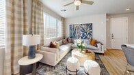 Located in Phoenix, AZ, this well-appointed one-bedroom, one-bathroom residence offers a thoughtfully designed single-floor layout with modern finishes throughout. Light wood-style flooring flows seamlessly across the open-concept living spaces, creating a cohesive and airy feel.

The kitchen is a standout feature, boasting gray shaker-style cabinetry, stainless steel appliances including a refrigerator, range, and microwave, a white quartz countertop island with bar seating, a subway tile backsplash, and pendant lighting. A stacked washer and dryer unit is conveniently integrated nearby.

The living room is bright and welcoming, with large windows dressed in plaid drapery that invite generous natural light and offer outdoor views. Ceiling fans are present in both the living room and bedroom, enhancing comfort throughout.

The bedroom features direct access to a private outdoor balcony, where exposed brick columns and open views of the surrounding community add character to the outdoor space. A walk-in closet with built-in shelving and hanging rods provides ample storage.

The bathroom includes gray shaker vanity cabinetry, a light countertop, and wood-look flooring continuing the space's cohesive design. The overall ambiance is warm, modern, and desert-inspired, reflecting the spirit of its Phoenix surroundings.