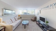 Located at 2047 Charlton Ave in Ann Arbor, Michigan, this one-bedroom, one-bathroom apartment at Charlton Apartments offers a thoughtfully laid-out single-floor living space. The open living room features plush carpeting, neutral toned walls, and large windows that allow abundant natural light to fill the room, creating a welcoming and airy atmosphere. The space flows seamlessly into a dedicated dining area near the entry, ideal for everyday meals.

The galley-style kitchen is efficiently designed with white shaker cabinetry, granite-patterned countertops, stainless steel appliances including an electric range and refrigerator, and light hardwood-style flooring. A stainless steel sink with modern fixtures adds a clean, functional touch.

The bedroom is a comfortable, carpeted retreat featuring a double-door closet with ample storage, a window with blinds for natural light and privacy, and a wall-mounted air conditioning unit. The room accommodates a full-sized bed with ease.

The bathroom is clean and straightforward, featuring a full tub-shower combination with white tile surround. Throughout the unit, the neutral color palette, practical layout, and well-maintained finishes make this a functional and comfortable living space in the heart of Ann Arbor.