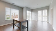Located at 750 E Broad St in Columbus, Ohio, this single-floor residence offers a thoughtfully designed layout with contemporary finishes throughout. The open living area is bathed in natural light through large windows and a sliding glass door that opens to a balcony, with light-toned hardwood-style flooring and neutral gray walls creating a clean, modern aesthetic.

The kitchen is a standout feature, outfitted with two-tone cabinetry — white upper cabinets and soft gray-blue lower cabinets — paired with a classic white subway tile backsplash, quartz-style countertops, and a full suite of stainless steel appliances including a refrigerator, range, microwave, and dishwasher. Pendant lighting adds a refined touch above the kitchen island.

The bedrooms are generously sized, each featuring plush carpeting, large windows with views of the surrounding Columbus neighborhood, and soft gray walls that lend a calm atmosphere. The bathrooms are distinctively finished with bold teal accent walls, white cabinetry with black hardware, light wood-tone flooring, and both a walk-in glass shower and a separate tub/shower combo. A dedicated in-unit laundry closet with a stacked washer and dryer adds everyday convenience to this well-appointed home.