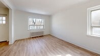 Located at 1650 Bathurst Street in Toronto's Forest Hill neighbourhood, this well-appointed 2-bedroom, 1-bathroom unit offers a thoughtfully laid-out single-floor plan. Light-toned hardwood flooring runs throughout, complementing the bright, white-painted walls that give the space a clean and airy feel. A welcoming entrance leads into the main living area, which features a charming arched doorway — a classic architectural detail that adds character to the open flow between rooms. Natural light filters in through multiple windows, enhancing the spacious feel of the living and bedroom areas, each fitted with traditional cast-iron radiators for efficient heating. The primary bedroom is a comfortable, well-proportioned room with a dedicated closet, while the second bedroom offers similar natural light and generous floor space. The galley-style kitchen is efficiently designed with white cabinetry, dark countertops, white subway tile backsplash, and stainless steel appliances including a range, microwave, and dishwasher. The bathroom features a full soaking tub surrounded by classic white subway tile walls, maintaining the unit's consistent clean aesthetic. Bold, dark three-panel interior doors provide a striking contrast against the white walls and light flooring throughout.