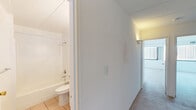 Located at 779 Eves Dr in Hillsborough, NJ, this well-laid-out residence offers two bedrooms, two bathrooms, and a comfortable single-floor plan. The open-concept kitchen and living room area serves as the heart of the home, with the kitchen featuring white cabinetry, dark countertops, a blue and white mosaic tile backsplash, tile flooring, a pendant light fixture, and white appliances including a refrigerator, range, and dishwasher. The living room extends from the kitchen and is finished with neutral carpet and a chandelier overhead, with sliding glass doors that lead to a private balcony with outdoor views. Both bedrooms are carpeted and bright, with the primary bedroom offering a large window with vertical blinds and generous natural light. Multiple closets throughout the unit provide ample storage. The two bathrooms are finished with tile flooring; one features a white vanity with under-cabinet storage, a mosaic tile backsplash, and a lighted mirror, while the other includes a full tub-shower combo. A connecting hallway ties the layout together efficiently. The overall aesthetic is clean and neutral throughout.