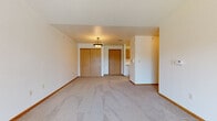 This single-floor unit at 1945 Mills St in Green Bay, Wisconsin, offers a straightforward and functional layout designed for comfortable everyday living. The open living area is finished with neutral carpet and features a pendant light fixture, a set of sliding closet doors with warm wood tones, and a front entry door. The space flows naturally toward the kitchen, making it easy to navigate between living and dining areas.

The kitchen is efficiently arranged in a U-shaped configuration, featuring oak cabinetry with ample upper and lower storage, white appliances including a range, over-the-range microwave, dishwasher, and refrigerator, along with light-toned vinyl flooring that contrasts cleanly with the warm wood cabinetry.

The bedroom is a comfortable, well-proportioned room with plush carpet, a ceiling fan with light kit, and a window that brings in natural light and outdoor views. A door provides access to additional storage or an adjoining space.

The bathroom is cleanly appointed with tile flooring, an oak vanity with storage drawers, a large wall mirror with a multi-bulb light fixture, and a full soaking tub with shower. A separate living area with vaulted ceilings and a sliding glass door leading to an outdoor balcony further enhances the unit's open, airy character.