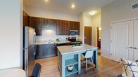 Located in the vibrant Northeast Minneapolis neighborhood, this single-floor residence at 38 Lowry Ave NE offers a thoughtfully designed layout with contemporary finishes throughout. The open-concept kitchen serves as the heart of the home, featuring rich dark wood cabinetry extending to the ceiling, granite countertops, stainless steel appliances including a refrigerator, microwave, and range, a double basin sink, and a central island with seating — ideal for both cooking and casual dining. The kitchen flows seamlessly into the living area, which is bathed in natural light from a large sliding glass door that opens to a private balcony with neighborhood views. The bedrooms are comfortably sized, carpeted for warmth, and feature generous windows that bring in ample daylight. At least one bedroom includes a walk-in closet with built-in shelving and hanging storage. The bathroom is well-appointed with dark wood cabinetry, a wide vanity with a full-width mirror, and light wood-look flooring that ties the space together. Throughout the residence, light hardwood-style flooring in the main living areas complements the neutral wall tones, creating a clean, modern aesthetic. This well-designed space combines functional living with contemporary style in one of Minneapolis's most sought-after neighborhoods.