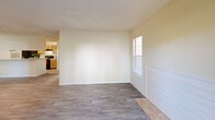Located at 100 Willow Oak Dr in Columbia, SC, this single-story, one-bedroom, two-bathroom home offers a functional and comfortable layout across a well-utilized floor plan. The open-concept living and dining area is finished with durable wood-look laminate flooring and features a textured ceiling, neutral warm-toned walls, and multiple windows fitted with horizontal blinds that invite ample natural light. A sliding glass door leads to a private balcony, extending the living space outdoors. The kitchen is defined by a wraparound peninsula with a light stone-style countertop, providing both prep space and a casual dining option. Warm wood-toned cabinetry, a black refrigerator, and a range complete the kitchen's practical layout. The bedroom is a comfortable size, featuring plush carpet, two windows overlooking the exterior, a textured ceiling, and a dedicated closet. Both bathrooms are finished with wood-toned cabinetry, a large vanity mirror, and a full tub-shower combination with tiled surround. Wood-look laminate flooring transitions to tile in the bathroom areas, maintaining a cohesive aesthetic throughout. The overall ambiance is clean, bright, and move-in ready, offering a straightforward and well-organized living environment.