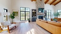 Located at 100 Star Blvd in Nashville, TN, this single-floor amenity space offers a thoughtfully designed layout across a generous footprint. The kitchen and living area is an architectural showpiece, boasting soaring vaulted ceilings with warm wood beam detailing and a tongue-and-groove wood ceiling that flows seamlessly into the space. A dramatic floor-to-ceiling stone fireplace anchors the living area, flanked by built-in cabinetry and a wall-mounted TV. Large black-framed grid windows flood the room with natural light and offer lush outdoor views. The chef-quality kitchen features navy shiplap cabinetry, a long white quartz island with woven rattan bar seating, stainless steel appliances, and woven pendant lighting suspended from the wood ceiling — all tied together by light hardwood flooring throughout. The exercise room is bright and well-appointed, housing treadmills, a rowing machine, a cable weight system, free weights, medicine balls, and wall-to-wall mirrors with mounted TVs for an energizing workout experience. The game room delivers entertainment for all ages, complete with a pool table, foosball table, air hockey table, a classic Pac-Man arcade cabinet, and a wall-mounted TV — making it an ideal social gathering space.