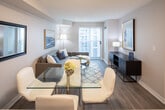 Located at 5191 Dundas St W in Toronto's Etobicoke neighbourhood, this single-floor unit presents a clean, contemporary design throughout. The open-concept layout connects the kitchen, dining, and living areas into one cohesive space, promoting an airy, functional flow ideal for everyday living and entertaining.

The kitchen is outfitted with white cabinetry, stainless steel appliances including a refrigerator, electric range, and built-in microwave, along with a peninsula featuring a double undermount sink and quartz countertops. Light tile flooring anchors the kitchen zone, transitioning seamlessly into wood-look flooring across the dining and living areas.

The combined dining and living space is bright and welcoming, with a large sliding door offering access to an outdoor area and allowing natural light to fill the room. The living area provides ample room for comfortable seating arrangements.

Two bedrooms are present, each finished with wood-look flooring and fitted with vertical blinds over windows. The primary bedroom features mirrored sliding closet doors that enhance the sense of space. The bathroom is finished with tile flooring, a vanity with an integrated sink, a large mirror, and a shower-tub combination. Throughout, the unit maintains a neutral, modern palette.