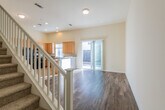 This two-story home offers a thoughtfully designed layout spread across two levels. The main floor opens into a bright living area with wood-style flooring and recessed lighting, anchored by a staircase with a classic white banister and carpeted treads. A sliding glass door fills the space with natural light and provides direct access to the outdoor patio area.

The kitchen is well-equipped, featuring light maple cabinetry, dark granite countertops, tile flooring, and a full suite of black appliances including a gas range, built-in microwave, dishwasher, and refrigerator. A tall pantry cabinet provides generous storage, and a window above the sink brings in additional natural light. A convenient powder room with a pedestal sink and round mirror is also located on the main level.

Upstairs, the bedrooms are carpeted and bathed in natural light through large windows fitted with blinds. The primary bedroom is generously proportioned and features multiple windows and an adjoining walk-in closet with wrap-around hanging rods and shelving. A full bathroom with a vanity, large mirror, and shower enclosure serves the upper level. Additional bedrooms offer comfortable proportions and ample natural light, making this home practical and inviting throughout.