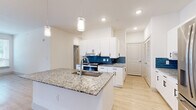 This single-story, 4-bedroom, 2-bathroom home offers a thoughtfully designed layout that balances function and comfort. The open-concept kitchen and living area serves as the heart of the home, highlighted by a large granite-topped island with an undermount sink and pendant lighting overhead. White shaker-style cabinetry, a vibrant blue tile backsplash, and stainless steel appliances — including a French door refrigerator — complete the kitchen's clean, modern aesthetic. Light wood-look flooring runs throughout the main living areas, enhancing the bright, airy atmosphere created by recessed lighting.

The four bedrooms offer a mix of flooring options, with some featuring plush carpet and others continuing the light wood-look floors. Several rooms include ceiling fans and windows with blinds that allow for natural light and ventilation. The primary bedroom connects to a spacious walk-in closet with built-in shelving and hanging rods, providing ample storage.

The bathrooms are finished with granite-topped vanities, white cabinetry, and light wood-look flooring. One bathroom features a tub-shower combo with white subway tile surround and accessibility grab bars. A dedicated laundry room with washer and dryer hookups adds everyday convenience, rounding out this well-equipped home.