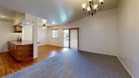 Located at 326 Rawson St in Dundee, Michigan, this single-floor, 2-bedroom, 1-bathroom unit offers a functional and well-organized layout across a comfortable footprint. The living and dining area is an inviting space highlighted by rich hardwood flooring, a ceiling fan, an elegant chandelier, and a sliding glass door that brings in natural light and provides outdoor access. The open pass-through kitchen connects seamlessly to the living area and features warm oak cabinetry, dark granite-style countertops, a double stainless steel sink, a stainless steel refrigerator, and a stainless range with overhead ventilation, all set atop hardwood floors. A breakfast bar-style counter adds additional workspace and casual dining potential. The two bedrooms are carpeted for comfort and feature neutral tones with white walls and clean trim. The primary bedroom includes a built-in closet with classic oak bi-fold doors, while the second bedroom benefits from a window with wooded views. Both bedrooms are served by a hallway connecting the private areas of the unit. The bathroom features a full tub-shower surround with built-in shelving. A dedicated laundry room houses a full-size washer and dryer, adding everyday convenience to this practical and well-appointed home.