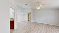 Located at 5537 Executive Dr in New Port Richey, Florida, this single-story, 3-bedroom, 3-bathroom home offers a comfortable and functional layout throughout. Light wood-look flooring flows through the main living areas and bedrooms, creating a bright, cohesive aesthetic complemented by neutral grey walls and white trim.

The living room is open and airy, featuring a ceiling fan with light fixture and a large window that fills the space with natural light. The primary bedroom is generously sized, boasting a sliding glass door that opens to an outdoor view, a ceiling fan, and access to a dedicated bathroom with a tiled walk-in shower. A walk-in closet with wire shelving provides ample storage.

The additional bedrooms each include ceiling fans and windows that invite natural light. The kitchen is well-appointed with warm wood cabinetry, granite countertops, tile flooring, and black appliances including a refrigerator, dishwasher, and range. A convenient in-unit laundry area with a washer and dryer is tucked just off the kitchen. The bathrooms feature wood vanities with light countertops, tiled tub-shower combinations, and clean, functional finishes throughout. An entrance area and hallway connect the rooms with ease, completing this well-organized and move-in-ready home.