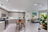 Located in Hialeah, FL, this well-appointed 2-bedroom, 2-bathroom residence offers a thoughtfully designed single-floor layout with modern finishes throughout. The open-concept kitchen and living area serves as the heart of the home, featuring sleek, floor-to-ceiling cabinetry in a warm gray wood-tone finish, white quartz countertops, stainless steel appliances, and a practical kitchen island with bar seating. Light wood-style flooring flows seamlessly throughout, enhancing the bright and airy atmosphere complemented by track lighting overhead. The living area extends toward large sliding glass doors that invite abundant natural light and offer views of lush greenery outside. The primary bedroom is a comfortable retreat with soft blue-gray accent walls, a dedicated closet, and direct access to an en-suite bathroom. The second bedroom mirrors this well-organized design with its own closet and ceiling fan. Both bathrooms are finished with large-format tile, featuring a soaking tub with shower combo and a glass-enclosed shower. A conveniently tucked in-unit washer adds everyday functionality. Two dedicated closets and a hallway complete this efficiently arranged, contemporary residence.
