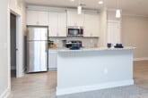 Located at 5746 Ruffin Rd in Greensboro, NC, this single-story unit offers a well-designed layout with consistent neutral tones and a blend of hard and soft flooring surfaces throughout. The kitchen is equipped with stainless steel appliances, including a refrigerator, electric range, and built-in microwave, complemented by white shaker-style cabinetry, granite countertops, a subway tile backsplash, and light hardwood-style flooring that extends into the entryway and adjoining areas.

The living area features plush carpeting, crown molding, a ceiling fan, and an open-plan connection to the kitchen via a granite-topped peninsula. A closet is conveniently located off the main living space. The bedrooms are carpeted and equipped with ceiling fans and windows with blinds; one bedroom features a double-door closet with wire shelving, while another includes its own closet and natural light.

Two bathrooms serve the unit, each finished with granite vanity tops, gray cabinetry, and tile flooring. One bathroom includes a tub/shower combination, while the other features a separate shower area. The dedicated laundry room houses a water heater, electrical panel, washer and dryer connections, and a wire storage shelf overhead.