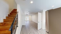 This two-story residence in Houma, Louisiana offers a clean, modern aesthetic defined by light wood-look flooring, crisp white walls, and recessed lighting throughout. The main living area on the lower level is bright and open, anchored by French doors that invite natural light and provide outdoor access. A ceiling fan overhead enhances airflow and comfort in this welcoming common space.

The kitchen is well-appointed with gray shaker-style cabinetry, light countertops, and a full suite of stainless steel appliances including a range, microwave, dishwasher, and refrigerator. A window above the sink adds natural light, while an adjacent closet houses a stacked washer and dryer for added convenience.

The two bedrooms each feature wood-look flooring, ceiling fans, and natural light from windows with blinds. Each bedroom is served by its own full bathroom equipped with a tub-shower combination and brushed gold fixtures, maintaining a cohesive, contemporary feel. A half bathroom serves guests on the main level.

A staircase with modern metal railings connects the two floors. Throughout the residence, the neutral palette, clean lines, and thoughtful layout create a functional and polished living environment.
