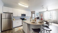 This single-floor, 4-bedroom, 4-bathroom unit in Memphis, Tennessee offers a contemporary layout designed to maximize functionality across its well-organized footprint. The open-concept kitchen serves as a central feature, showcasing white shaker-style cabinetry extending to the ceiling, granite countertops, stainless steel appliances including a refrigerator, range, and microwave, and a distinctive curved island with an integrated sink and bar seating — ideal for casual dining or entertaining. Wood-style plank flooring runs throughout the main living areas, complementing the neutral gray walls and creating a cohesive, modern aesthetic.

The living area connects directly to the kitchen and features a ceiling fan and windows that allow natural light to filter through. Each of the four bedrooms is carpeted and includes a closet, with windows providing natural light and a comfortable, private atmosphere. The bedrooms vary slightly in configuration but maintain a consistent, clean design. Each bedroom is paired with its own full bathroom, finished with granite-topped vanities, white cabinetry, wood-style flooring, and shower-tub combinations. A hallway connects the rooms efficiently, rounding out this well-appointed, roommate-friendly layout.