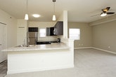 This single-floor unit presents a thoughtfully designed layout that balances functionality with comfort. The kitchen serves as a standout feature, equipped with rich dark espresso cabinetry, light granite-style countertops, and a full suite of stainless steel appliances including a gas range, built-in microwave, and dishwasher. Pendant lighting accents the space, while tile flooring adds durability underfoot. A peninsula with a double basin sink creates a natural transition into the open living area.

The living space is finished with plush neutral carpeting and painted in warm beige tones, contributing to an inviting ambiance. A ceiling fan provides comfort, and a large sliding glass door opens to a private balcony, allowing ample natural light and outdoor views. A secondary bedroom features its own ceiling fan, a window with blinds, and a reach-in closet with built-in shelving for organized storage.

The bathroom includes a dark-cabineted vanity topped with granite-style counters, an oversized mirror with overhead lighting, and tile flooring. Throughout the unit, clean white trim and neutral wall tones create a cohesive, modern aesthetic. The 3D floor plan reveals a compact yet efficiently arranged floor plan with distinct zones for living, cooking, sleeping, and bathing.