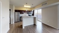 This well-appointed single-floor residence offers a thoughtfully designed layout that balances open communal spaces with comfortable private quarters. The living area is a standout, featuring rich hardwood-style flooring, a wall-mounted modern fireplace, and a sliding glass door that opens to a private balcony, allowing natural light to fill the space and providing pleasant outdoor views.

The kitchen is both functional and stylish, showcasing dark espresso cabinetry, granite-style countertops, a double-basin stainless steel sink, and a full suite of stainless steel appliances including a refrigerator, microwave, range, and dishwasher. A central island with pendant lighting above serves as an ideal space for casual dining or meal preparation, while seamlessly connecting to the living and dining area.

The bedroom is generously sized, featuring plush wall-to-wall carpeting and a built-in closet with sliding doors and integrated shelving and hanging rods for ample storage. A second door from the bedroom provides convenient access to adjacent spaces. The bathroom includes a full-size soaking tub and shower combination with clean white surrounds and chrome fixtures, offering a crisp, well-maintained aesthetic throughout. The overall ambiance is clean, modern, and move-in ready.