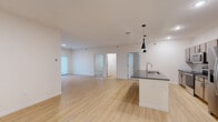 This single-floor unit offers five bedrooms and two bathrooms within a well-designed, contemporary layout. The open-concept kitchen and living area serves as the central hub of the space, featuring light hardwood-style flooring, recessed lighting, and sleek pendant lights above a kitchen island with a dark countertop and integrated sink. The kitchen is equipped with stainless steel appliances, including a range, microwave, and refrigerator, complemented by gray cabinetry and a tile backsplash.

The living area flows seamlessly from the kitchen, providing an expansive, bright environment with access to additional rooms. The primary bedroom includes sliding glass doors fitted with vertical blinds, allowing natural light and outdoor access. The remaining bedrooms are carpeted, offering a comfortable feel, with windows providing natural light.

The two bathrooms are finished to a modern standard. The primary bathroom features a dual-sink vanity with a dark countertop, light wood cabinetry, a large mirror, and marble-style tile flooring. The secondary bathroom includes a single-sink vanity and a shower-tub combination. A dedicated closet provides additional storage within the unit.