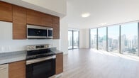 Located in the heart of downtown Miami at 99 NE Fourth St, this high-rise unit offers a sleek, modern living experience defined by clean lines and contemporary design. The open-concept kitchen and living area is a standout feature, with floor-to-ceiling glass windows and sliding balcony access that frame breathtaking panoramic views of the Miami skyline and beyond, flooding the space with abundant natural light.

The kitchen is thoughtfully appointed with rich walnut-toned cabinetry, granite countertops, a full suite of stainless steel appliances including a range, microwave, dishwasher, and refrigerator with ice maker, along with frosted glass upper cabinet accents that add a refined touch. Light wood-toned flooring runs seamlessly throughout the living areas and bedrooms, contributing to a warm yet modern aesthetic.

The bedroom continues the floor-to-ceiling window theme, delivering striking elevated city views and generous natural light. A spacious walk-in closet with built-in shelving and hanging rods provides ample storage. The bathroom is finished with marble-look tile on both the floors and tub surround, complemented by a wood-framed vanity with granite countertop and an oversized mirror. The overall ambiance is bright, airy, and polished, reflecting the best of contemporary urban living in Miami.