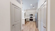 Located at 8157 Ederville Rd in Fort Worth, TX, this one-bedroom, one-bathroom residence offers a thoughtfully designed single-floor layout with modern finishes throughout. The open-concept kitchen is a standout feature, equipped with stainless steel appliances — including a French door refrigerator, electric range, over-the-range microwave, and dishwasher — complemented by gray shaker-style cabinetry, a white quartz countertop, a peninsula with pendant lighting, and warm wood-look luxury vinyl flooring. The living area extends naturally from the kitchen, featuring ceiling fan and sliding glass doors that invite natural light and provide outdoor access. The spacious bedroom is finished with plush carpet, a ceiling fan, and a window with blinds, creating a comfortable retreat. The full bathroom is well-appointed with a dual-sink vanity featuring gray cabinetry and brushed gold hardware, a soaking tub with a tiled surround, and wood-look flooring. Adjacent to the bathroom is a generous walk-in closet outfitted with built-in shelving and a hanging rod, offering ample storage. The neutral color palette and clean architectural lines throughout lend the space a fresh, contemporary ambiance.