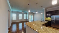 Located in Conroe, TX, this single-story 3-bedroom, 2-bathroom home offers a well-designed open-concept layout that seamlessly connects the living, dining, and kitchen areas. The kitchen is a standout, featuring rich dark cabinetry, granite countertops, a tile backsplash, stainless steel appliances including a refrigerator, range, and microwave, and a large peninsula with an undermount sink — ideal for both cooking and entertaining. A walk-in pantry provides generous storage. Hardwood-style flooring flows throughout the main living areas, complemented by crown molding and neutral tones that lend a clean, polished look. The living area is brightened by multiple windows, pendant and track lighting, and a ceiling fan, with sliding glass doors opening to a private balcony with outdoor views. The primary suite includes its own en-suite bathroom equipped with a soaking tub, separate glass-enclosed shower, and granite vanity. The secondary bathroom mirrors the refined finishes with a tiled tub-shower combo and granite countertop. The additional bedrooms feature plush carpeting, crown molding, and walk-in closets, offering comfortable and practical living spaces throughout.