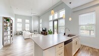 Located in Cleveland's vibrant Ohio City neighborhood, this modern 4-bedroom, 3-bathroom home offers a thoughtfully designed open-concept layout with striking architectural details throughout. The living and kitchen area is anchored by soaring double-height ceilings, an abundance of natural light from oversized windows, and warm wood-look flooring. The kitchen is well-appointed with white shaker cabinetry, stainless steel appliances including a dishwasher, microwave, and range, a decorative tile backsplash, a large peninsula with pendant lighting, and a deep undermount sink. The living room benefits from the dramatic ceiling height and direct access to an expansive outdoor deck, which features composite decking and sleek black railings with panoramic views of the surrounding neighborhood. The four bedrooms are generously proportioned, with the primary suite offering a spacious walk-in closet and a dedicated en-suite bathroom. The primary bath includes a dual-sink vanity with rich dark wood cabinetry, a large mirror, tile flooring, and a walk-in shower. Additional bedrooms feature plush carpeting and tall windows. A wide, light-filled hallway connects all rooms with clean lines, dark-framed doors, and a neutral color palette that contributes to the home's modern, cohesive aesthetic.