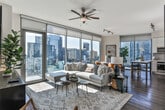 Located in the heart of Buckhead at 3360 Peachtree Rd NE, Atlanta, this single-floor residence offers a thoughtfully designed layout with modern finishes throughout. The entryway sets a refined tone, featuring dark hardwood flooring, a louvered utility door concealing an in-unit stacked Whirlpool washer and dryer, and a stylish console beneath a round wood-framed mirror.

The living area is bright and open, with floor-to-ceiling windows and sliding glass doors that lead to a private balcony overlooking the Atlanta skyline. Dark hardwood floors continue throughout, anchoring the contemporary aesthetic.

The kitchen is outfitted with stainless steel appliances, including a built-in oven, electric cooktop, over-the-range microwave, French door refrigerator, and dishwasher. Light wood cabinetry, glossy white upper cabinets, a grey subway tile backsplash, and white quartz countertops complete the polished look. Expansive windows flood the kitchen with natural light and sweeping city views.

The bedroom is a calm retreat with soft neutral tones and plush carpeting. The bathroom features large-format tile flooring, a light wood vanity, and a tub-shower combination adorned with full marble-look tile surround, creating a clean, spa-inspired atmosphere.