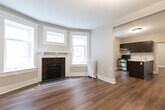 Located at 42 Maitland St in Toronto's vibrant Church-Wellesley neighbourhood, this 2-bedroom, 1-bathroom unit thoughtfully combines historic character with contemporary finishes. Hardwood flooring flows throughout, providing warmth and continuity across every room.

The living room is a standout, anchored by a classic fireplace with a dark tile surround and decorative mantel. A charming bay window with leaded glass transoms floods the space with natural light, while a cast-iron radiator adds to the heritage appeal.

The kitchen features dark espresso cabinetry, stainless steel appliances including a full-size refrigerator and electric range, and sleek white countertops. A decorative stained glass window above the sink area adds a distinctive artistic touch.

Both bedrooms are bright and well-proportioned, benefiting from large windows with traditional trim detailing. The second bedroom includes a cast-iron radiator, continuing the heritage aesthetic. The hallway offers practical access between rooms with classic white panel doors and trim.

The bathroom is finished with white subway-style tiles, a contrasting black mosaic accent border, a classic basketweave tile floor, and a glass-enclosed shower, creating a clean and timeless aesthetic throughout.