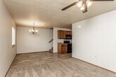 This two-floor home offers a practical and comfortable layout with a welcoming open-concept main living area. The living room features warm carpeted flooring, a ceiling fan with light fixture, and a decorative chandelier, creating an inviting atmosphere that flows seamlessly into the kitchen. The kitchen is well-equipped with rich, dark wood cabinetry, granite-style countertops, black appliances including an electric range, microwave, and ample storage, complemented by wood-look plank flooring. A staircase connects the two floors, with the upper level housing multiple bedrooms. Each bedroom is carpeted and includes a window with blinds for natural light, and at least one features a dedicated closet with built-in shelving. The bathrooms are finished with wood-look plank flooring, warm wood vanities with granite-style countertops, and black hardware accents. One bathroom includes a full tub-shower combination, while another features a half-bath configuration. A spacious walk-in closet with multi-level shelving and hanging rods provides generous storage. Throughout the home, neutral wall tones and consistent finishes create a cohesive and move-in-ready environment.