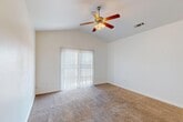 Located at 214 E Cameron Ave in Visalia, CA, this single-story, 2-bedroom, 2-bathroom home offers a well-organized layout designed for comfortable living. The living room is a standout space, featuring vaulted ceilings and a ceiling fan with a light fixture, creating an airy, open atmosphere. Plush wall-to-wall carpeting flows throughout, and a sliding glass door fitted with vertical blinds fills the room with natural light while providing outdoor access. The adjoining dining area is highlighted by a pendant light fixture and transitions seamlessly into the tiled kitchen. The kitchen is equipped with warm oak cabinetry, tile backsplash, a gas range, built-in microwave, dishwasher, refrigerator, and a double-basin sink beneath a window. The spacious primary bedroom features vaulted ceilings, a ceiling fan, a dedicated closet, and natural light from a window with blinds. The second bedroom is bright and well-proportioned with carpeted floors and a window. Both bathrooms include oak vanities with tile-topped counters, large mirrors, and tile flooring. A dedicated closet provides additional storage. Clean white walls and consistent finishes throughout give the home a cohesive, move-in-ready feel.