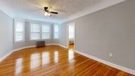 Located at 9907 Lake Rd in Cleveland's 44102 neighborhood, this single-floor, 3-bedroom, 1-bathroom residence offers a practical and well-appointed layout. Gleaming hardwood floors run throughout the bedrooms and hallway, catching natural light and lending warmth to the neutral gray-painted walls. The spacious primary bedroom is a standout feature, with a angled bay-style window arrangement, a ceiling fan with light fixture, a classic cast-iron radiator, and a textured ceiling. The two additional bedrooms are well-proportioned, each with hardwood floors, ceiling fans, natural window light, and cast-iron radiators. The bedrooms are served by five closets in total, providing generous storage throughout. The kitchen is equipped with warm wood cabinetry, dark countertops, a white gas range, tile backsplash, and resilient flooring. The bathroom is finished in crisp white with a full tub-shower combo, a mosaic tile floor, a pedestal sink, and a glass block window that provides privacy while allowing diffused natural light. Clean white trim and consistent gray-toned walls unify the home's interior, creating a cohesive and move-in-ready aesthetic throughout.