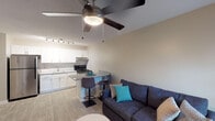 Located at 400 Hawk Ridge Dr in Clemmons, NC, this single-floor residence offers a thoughtfully designed layout that maximizes both function and comfort. The open-concept living and kitchen area serves as the heart of the home, where light wood-look flooring and neutral walls create a clean, cohesive aesthetic. The kitchen is equipped with stainless steel appliances, including a refrigerator and range, complemented by crisp white shaker-style cabinetry, a classic subway tile backsplash, and granite-look countertops. A peninsula with bar seating bridges the kitchen and living space, making it ideal for casual dining and entertaining. Track lighting overhead ensures the kitchen is well-lit and functional. The living area is bright and welcoming, featuring a ceiling fan with light fixture and a window dressed with decorative curtains that allow natural light to filter in. The bedroom offers a relaxed atmosphere with carpeted flooring, a ceiling fan, a window with natural light, and a closet for ample storage. The bathroom is finished with a granite-topped vanity, white cabinetry, a large mirror, and brushed nickel fixtures, providing a polished and practical space. Throughout, the residence maintains a consistent, modern design with neutral tones and quality finishes.