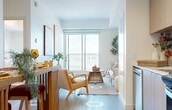 Located in the heart of Edmonton's Oliver neighbourhood at 10135 108 Street NW, this well-designed one-bedroom, one-bathroom unit offers a thoughtfully organized open-concept layout across a single floor. Light wood-look flooring runs throughout, complementing the clean white walls and creating a bright, cohesive aesthetic.

The kitchen is equipped with flat-panel light oak cabinetry, stainless steel appliances including a refrigerator, range, and over-the-range microwave, and a textured tile backsplash. A compact bar-height dining area with a slatted wood railing adjoins the kitchen, making efficient use of the space.

The living room benefits from a large sliding glass door that opens to a balcony with open city views, allowing generous natural light to fill the room. The bedroom features a tray ceiling detail, a window with urban views, and a closet with built-in hanging storage. The bathroom is finished with full-height neutral tile surrounding a soaker tub-shower combination, complemented by tile flooring.

Throughout the unit, recessed and track lighting provide flexible illumination, and the overall design prioritizes clean lines and a modern, functional aesthetic suited for urban living in downtown Edmonton.