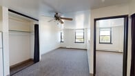 Located at 1720 S 29th St in Milwaukee, WI, this two-bedroom, one-bathroom unit offers a practical and functional layout across a single floor. The space is designed for efficient living, with carpeted flooring throughout the main living and bedroom areas, contributing to a warm and quiet atmosphere.

The primary bedroom is a well-proportioned room featuring multiple windows with black frames that invite natural light and offer views of the surrounding neighborhood. A ceiling fan adds comfort and airflow, while a closet with a hanging rod — enclosed by a curtain panel — provides convenient storage. Baseboard heating runs along the walls for year-round comfort.

The second bedroom mirrors the clean, simple aesthetic with its own window and carpeted floor, making it suitable as a guest room, home office, or additional sleeping space.

The kitchen is equipped with wood-toned cabinetry featuring classic hardware, light countertops, a white refrigerator, and a gas range — offering essential functionality in a compact footprint. The bathroom includes a full tub and shower combination with grab bars, a toilet, and a vanity with storage, finished with tile flooring for easy maintenance.

A dedicated closet provides additional storage, rounding out this straightforward and practical residential unit in Milwaukee's south side.