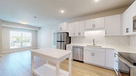 This well-appointed 2-bedroom, 1-bathroom unit in Waconia, Minnesota offers a thoughtfully designed single-floor layout that balances modern style with everyday functionality. The open-concept kitchen and living area serves as the heart of the home, featuring crisp white shaker cabinetry with matte black hardware, white quartz countertops, a classic subway tile backsplash, and a full suite of stainless steel appliances including a refrigerator, range, microwave, and dishwasher. Light-toned luxury vinyl plank flooring runs throughout the main living areas, enhancing the bright and airy atmosphere created by recessed lighting and natural light from surrounding windows. The generously sized primary bedroom offers plush carpeting, a walk-in closet, and direct access to the bathroom, which is finished with white cabinetry, quartz countertops, and clean, contemporary fixtures. The second bedroom is well-proportioned with soft carpet flooring and a large window that invites ample natural light. A dedicated closet provides additional storage. Neutral wall tones and clean architectural lines throughout the unit create a cohesive, move-in-ready aesthetic suited for a variety of living styles.