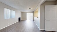 Located at 3571 Madison St in Riverside, California, this single-floor residence offers a functional and comfortable layout with two bedrooms and two full bathrooms. The living room serves as the heart of the home, featuring a wood-burning fireplace, neutral-toned walls, durable wood-look flooring, and a sliding glass door fitted with vertical blinds that allows natural light to fill the space. Adjacent to the living area, the kitchen is equipped with white cabinetry, a gas range, built-in microwave, dishwasher, and a stone-toned countertop, all illuminated by a skylight-style ceiling panel. A pass-through counter connects the kitchen to the living area, enhancing the open feel. The primary bedroom offers a generous footprint with plush carpeting, a closet, and a window overlooking the exterior. The second bedroom is similarly appointed with carpet and a closet. Both bathrooms are finished with wood-look flooring, full tub-shower combinations, and clean white fixtures. A dedicated entrance and two closets provide practical storage throughout. The textured ceilings and warm, neutral palette lend a cohesive and understated aesthetic to the entire residence.