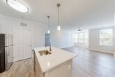 Located at 75 Parkview St in Weymouth, MA, this well-designed 2-bedroom, 2-bathroom home offers a thoughtful single-floor layout with modern finishes throughout. The open-concept kitchen and living area serves as the heart of the home, anchored by a central island with a white quartz countertop, an undermount stainless steel sink, and stylish pendant lighting. The kitchen features gray shaker-style cabinetry, stainless steel appliances including a refrigerator, range, and microwave, all set atop light wood-look flooring that flows seamlessly into the living area. Crown molding adds an elegant architectural touch, while a ceiling fan and large windows allow for ample natural light and views of the surrounding greenery. Both bedrooms are finished with plush carpeting and bright windows, creating comfortable, light-filled retreats. The primary bedroom is generously sized and includes a dedicated walk-in closet outfitted with wire shelving for organized storage. The bathrooms are clean and functional, with one featuring a walk-in shower with a grab bar. A dedicated in-unit laundry area adds everyday convenience. The second bedroom features hardwood-style flooring and corner windows. This home combines practical amenities with a clean, contemporary aesthetic.