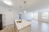 Located at 75 Parkview St in Weymouth, MA, this well-designed 2-bedroom, 2-bathroom home offers a thoughtful single-floor layout with modern finishes throughout. The open-concept kitchen and living area serves as the heart of the home, anchored by a central island with a white quartz countertop, an undermount stainless steel sink, and stylish pendant lighting. The kitchen features gray shaker-style cabinetry, stainless steel appliances including a refrigerator, range, and microwave, all set atop light wood-look flooring that flows seamlessly into the living area. Crown molding adds an elegant architectural touch, while a ceiling fan and large windows allow for ample natural light and views of the surrounding greenery. Both bedrooms are finished with plush carpeting and bright windows, creating comfortable, light-filled retreats. The primary bedroom is generously sized and includes a dedicated walk-in closet outfitted with wire shelving for organized storage. The bathrooms are clean and functional, with one featuring a walk-in shower with a grab bar. A dedicated in-unit laundry area adds everyday convenience. The second bedroom features hardwood-style flooring and corner windows. This home combines practical amenities with a clean, contemporary aesthetic.